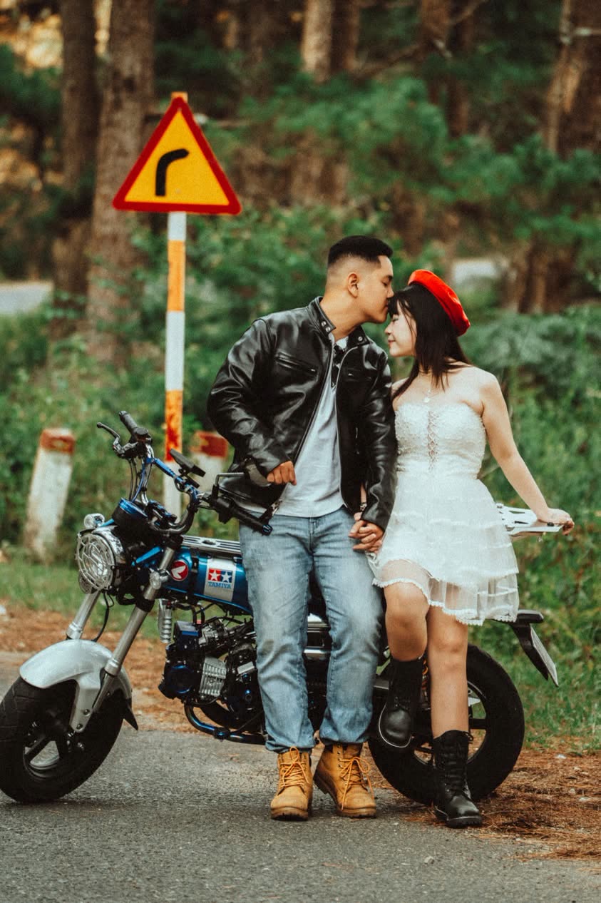 Cặp đôi bên chiếc mô tô cạnh biển báo đường đèo